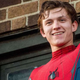 Tom Holland in the Spider-Man costume, smiling and waving.